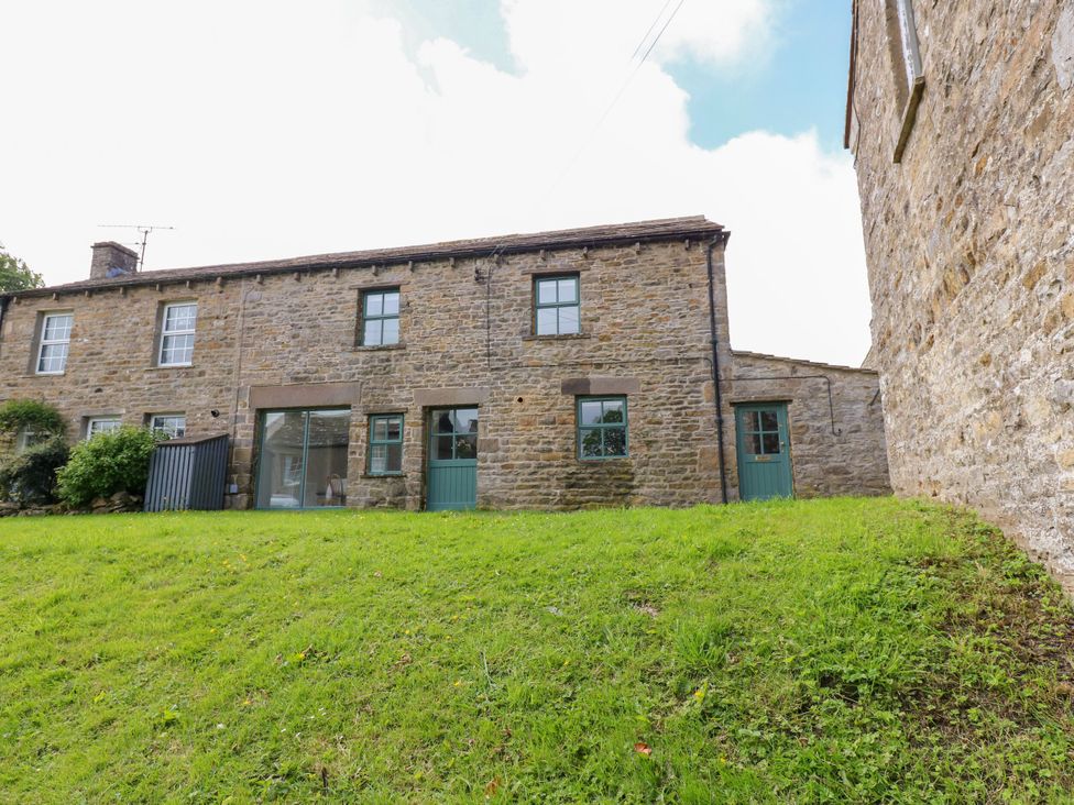 A stone building with green doors and windows at High Meadow Barn Thornton Rust near Bainbridge