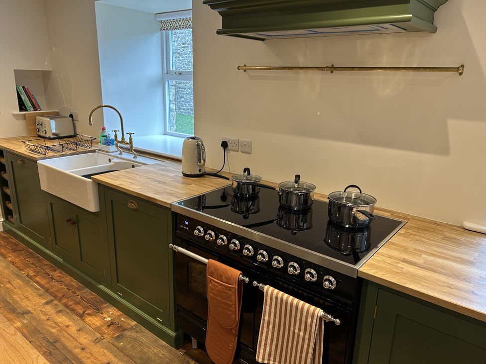 A kitchen with a sink stove and cooking pots at High Meadow Barn Thornton Rust near Bainbridge