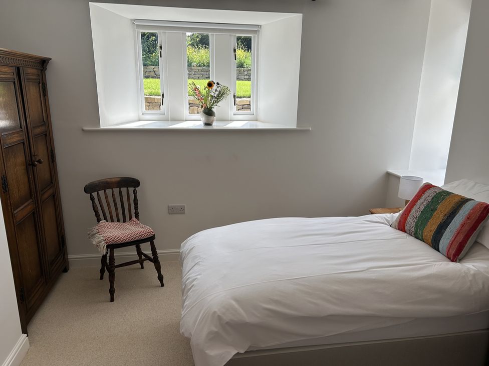 A bedroom with a bed and a chair at High Meadow Barn Thornton Rust near Bainbridge