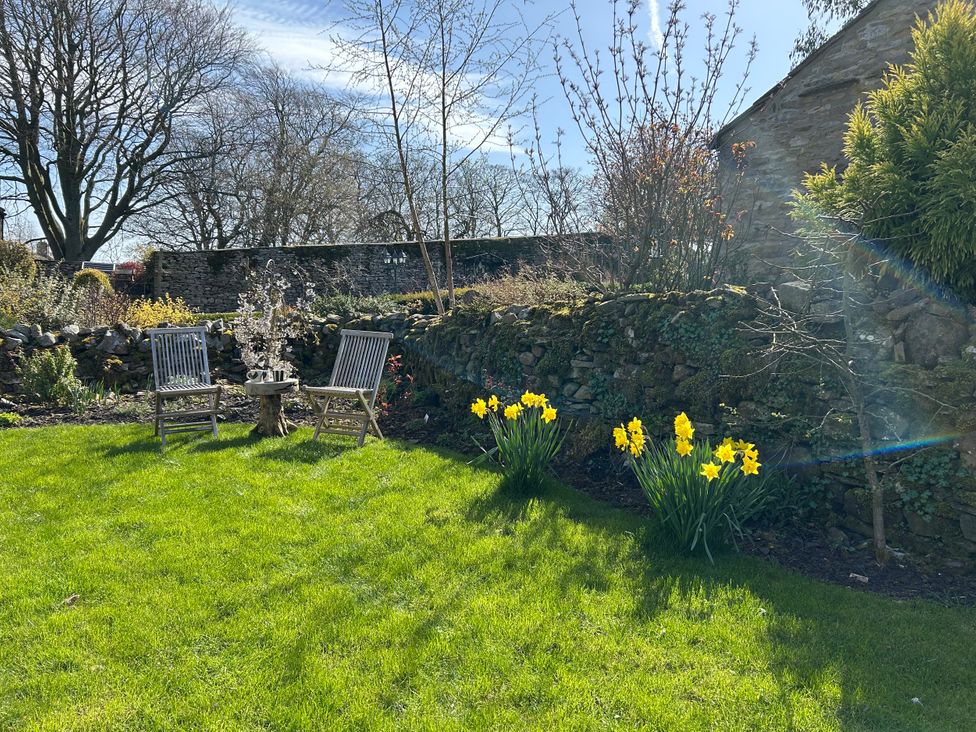 A garden with chairs, a table, and flowers at High Meadow Barn in Thornton Rust near Bainbridge
