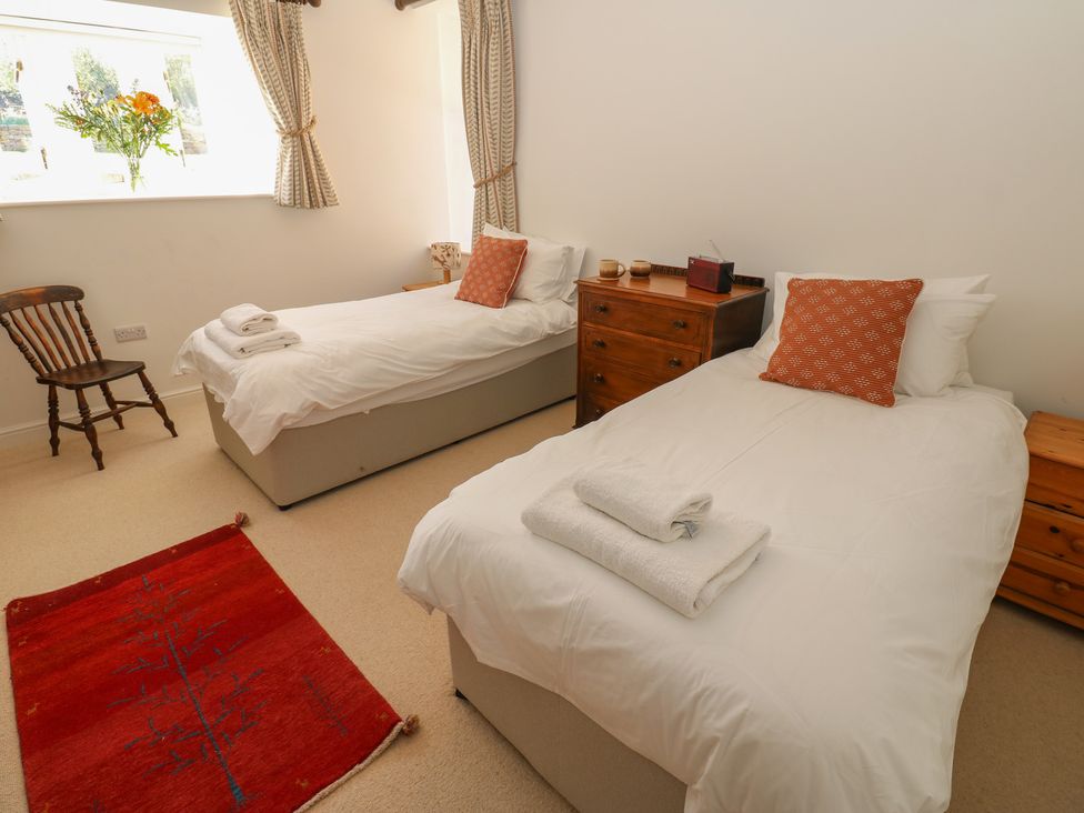 A bedroom with two beds and a chair at High Meadow Barn Thornton Rust near Bainbridge