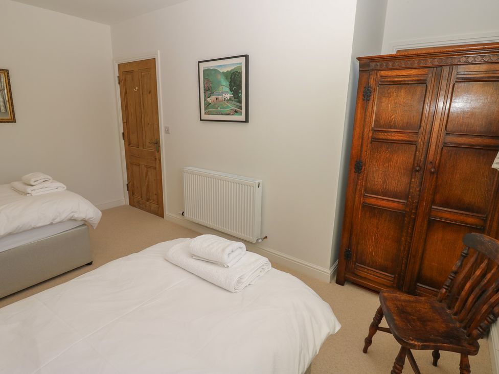 A bedroom with two beds and a wardrobe at High Meadow Barn in Thornton Rust near Bainbridge