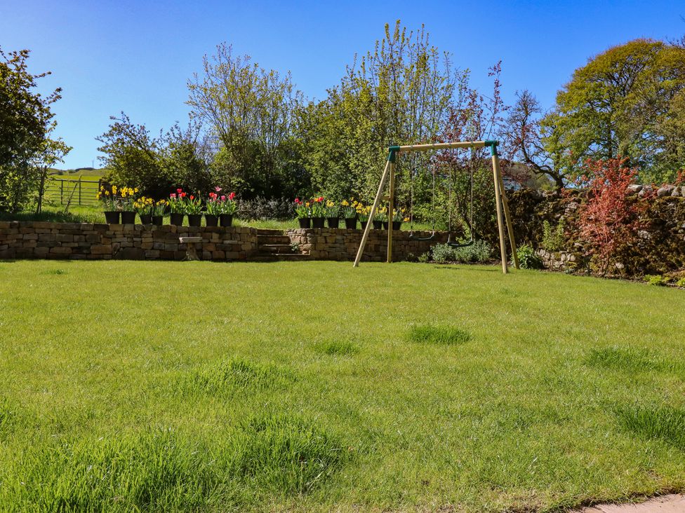A garden with a swing and flowerpots at High Meadow Barn Thornton Rust near Bainbridge