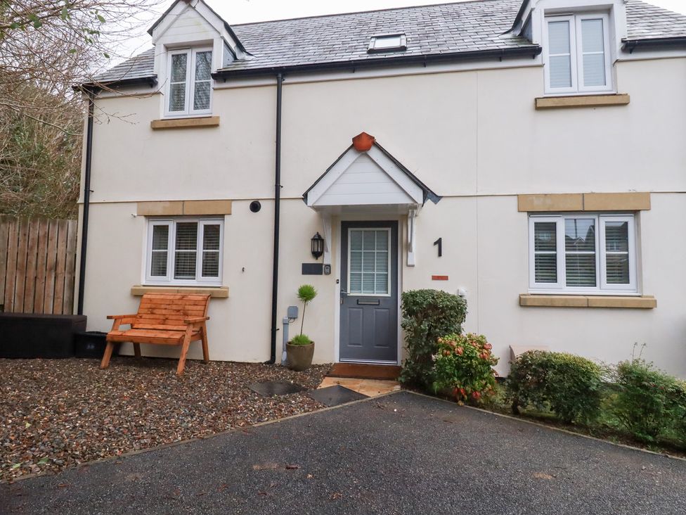 An outdoor view of a house with a bench and plants at Poldam in St Austell