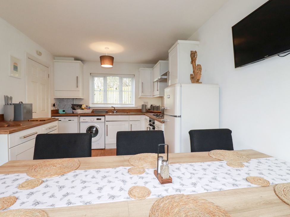 A kitchen with appliances and dining table at Poldam St Austell