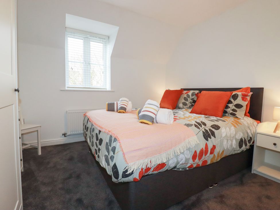 A bedroom with a large bed and a nightstand at Poldam in St Austell