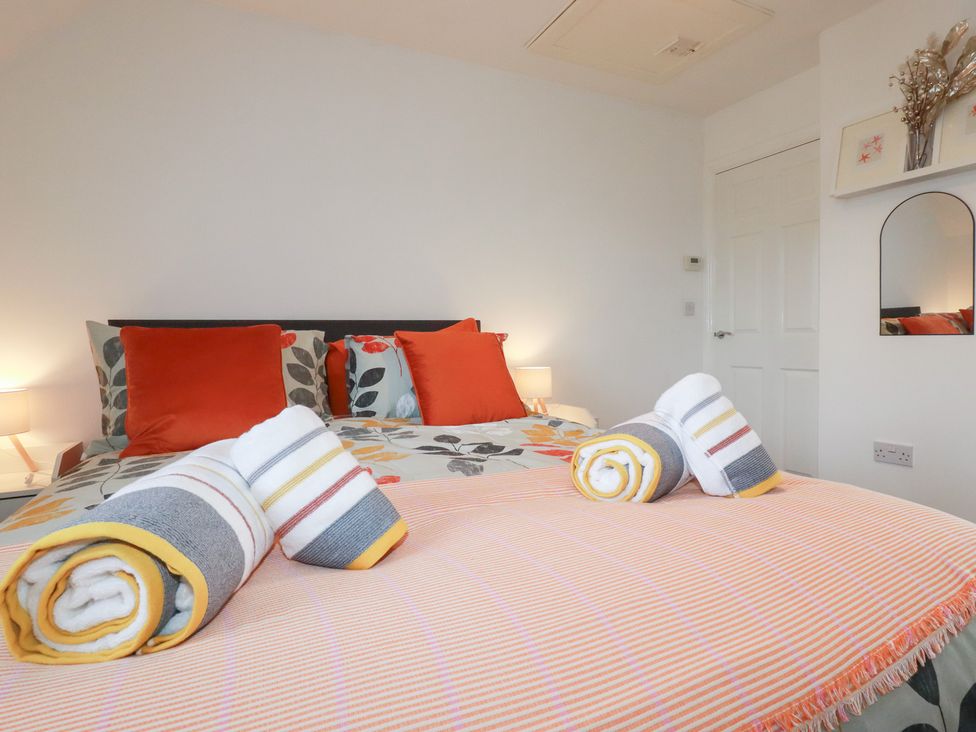 A bedroom with a bed and towels at Poldam in St Austell