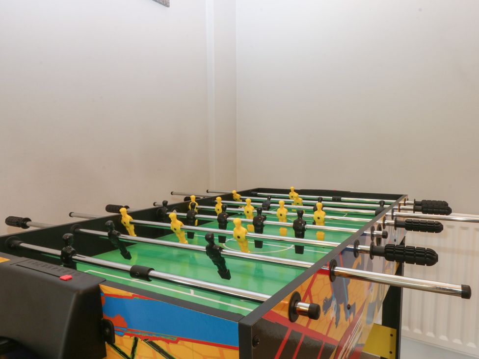 A foosball table with yellow and black players in a game room at Ty Llwyd, Llandudno
