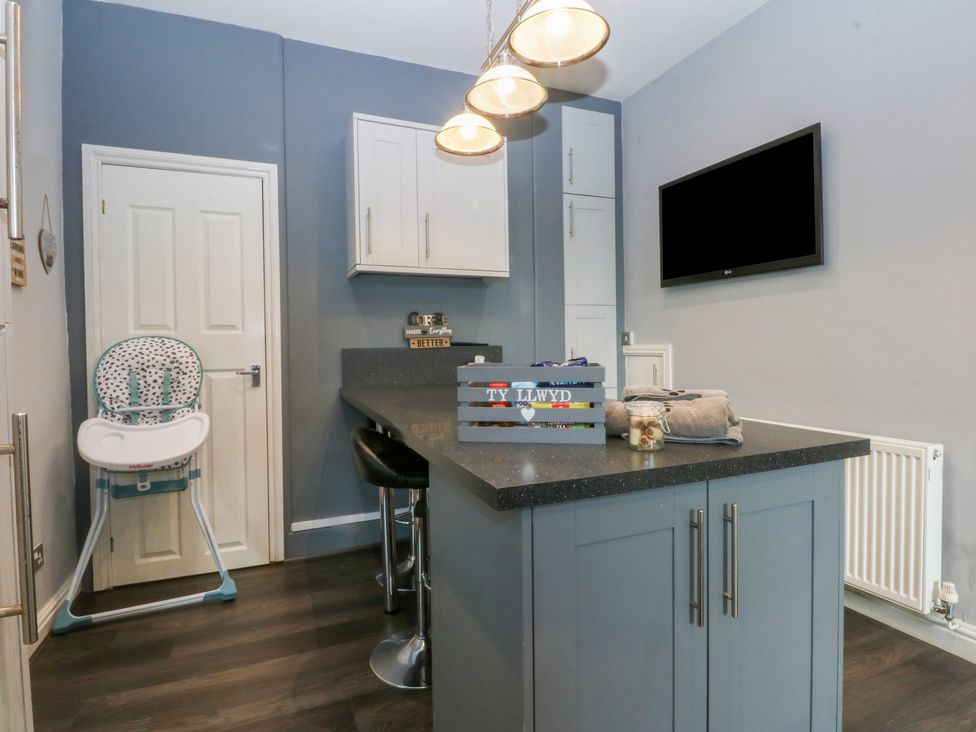 A kitchen with a kitchen island and high chair at Ty Llwyd in Llandudno