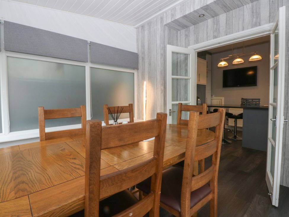 A dining room with a wooden table and chairs at Ty Llwyd in Llandudno