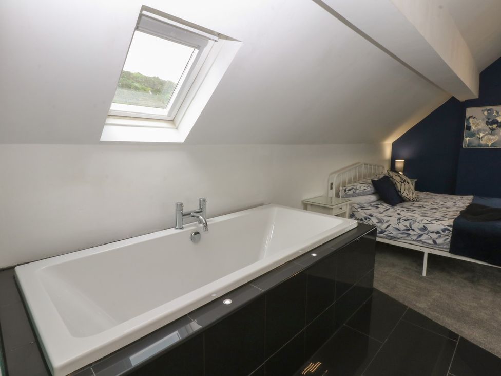 A bedroom with a bathtub and bed at Ty Llwyd in Llandudno