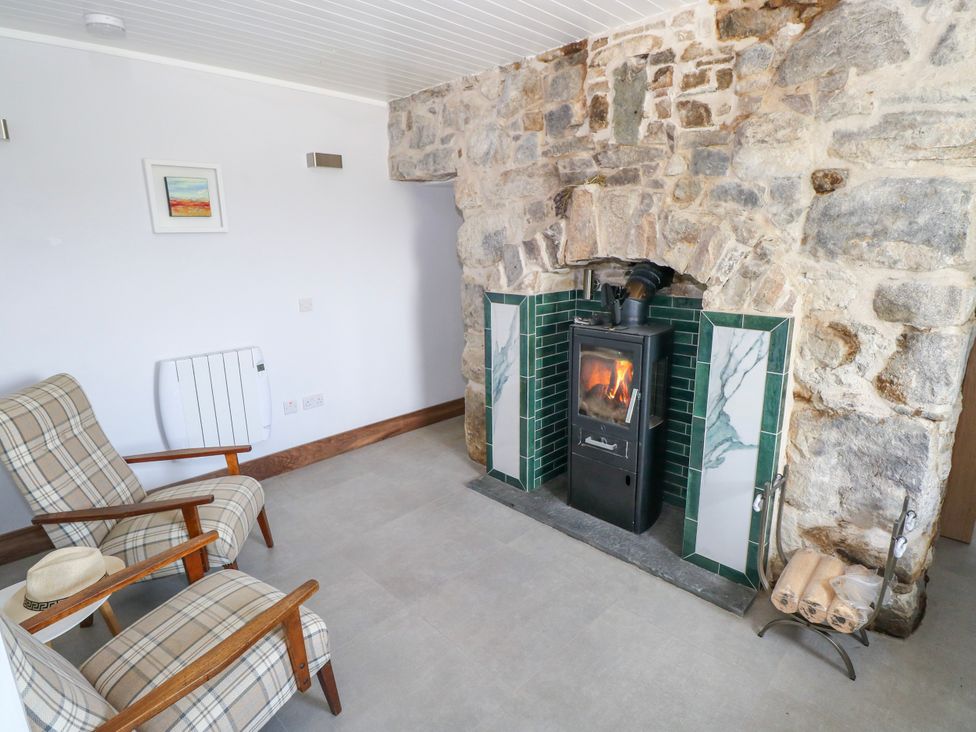 A sitting room with a wood stove and two armchairs at Claddagh Tuss Holiday Cottage Clifton