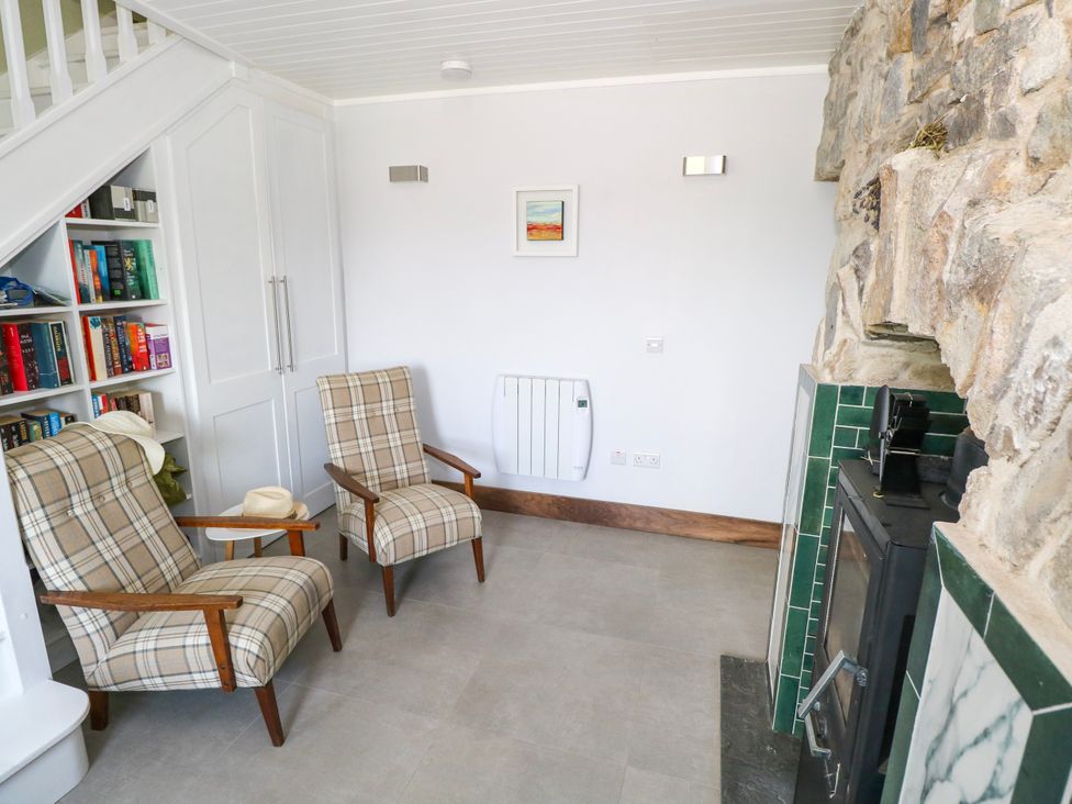A living room with two chairs and a bookshelf at Claddagh Tuss Holiday Cottage in Clifton