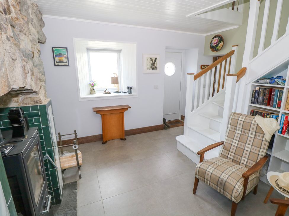 A living room with a stove and bookshelf at Claddagh Tuss Holiday Cottage in Clifton