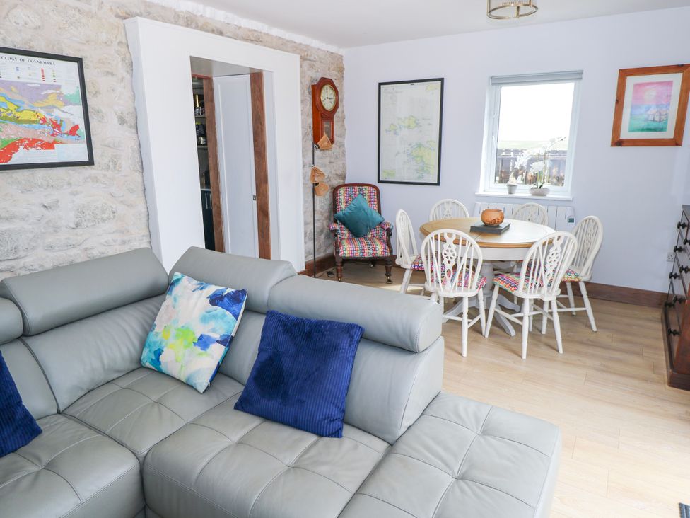 A living room with a sofa and dining area at Claddagh Tuss Holiday Cottage in Clifton