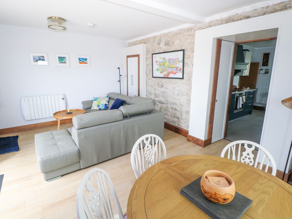 A living room with a sofa and dining table at Claddagh Tuss Holiday Cottage in Clifton