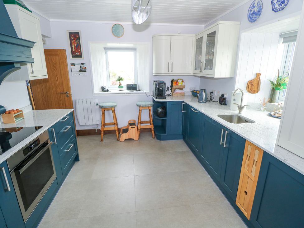 A kitchen with blue cabinets and stools at Claddagh Tuss Holiday Cottage in Clifton