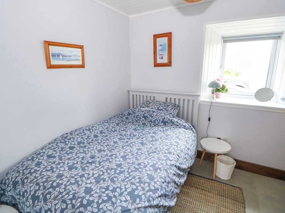 A bedroom with a bed and bedside table at Claddagh Tuss Holiday Cottage Clifton