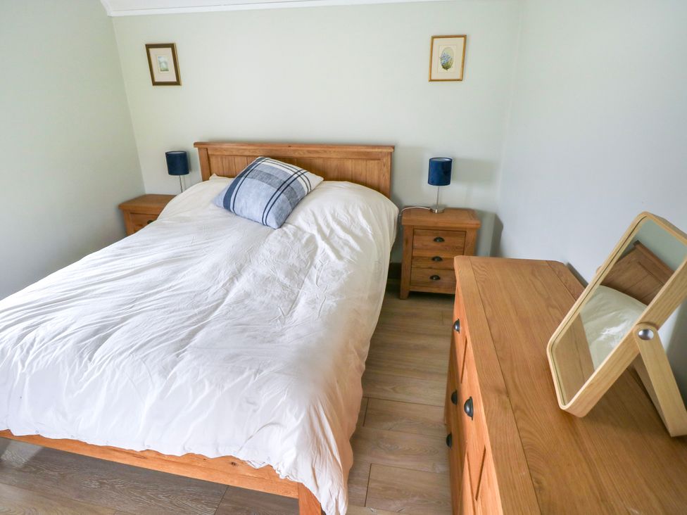 A bedroom with a bed and nightstand at Claddagh Tuss Holiday Cottage in Clifton