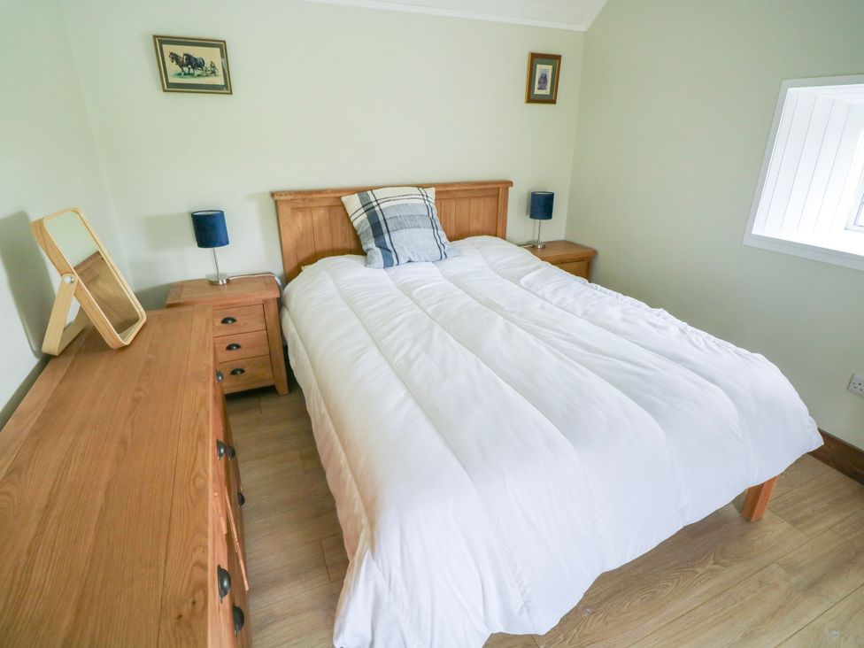 A bedroom with a bed and a dressing table at Claddagh Tuss Holiday Cottage, Clifton