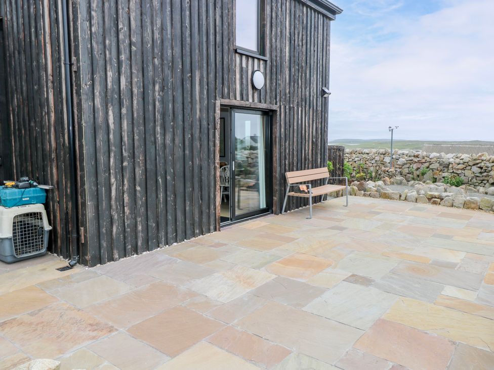 An outdoor patio with a bench and pet carrier at Claddagh Tuss Holiday Cottage Clifton