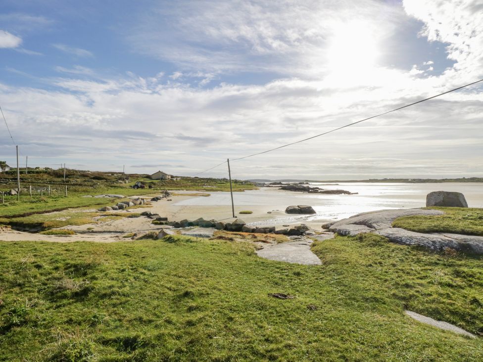 A landscape with grass, rocks, and water at Claddagh Tuss Holiday Cottage Clifton