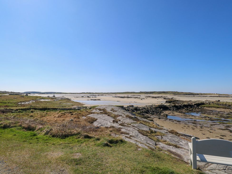 A coastal landscape featuring sand, rocks, and a bench at Claddagh Tuss Holiday Cottage, Clifton