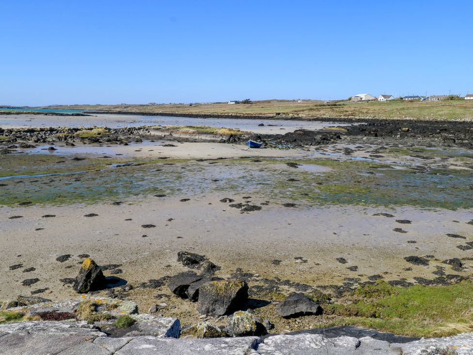 A shore with rocks and a boat at Claddagh Tuss Holiday Cottage in Clifton