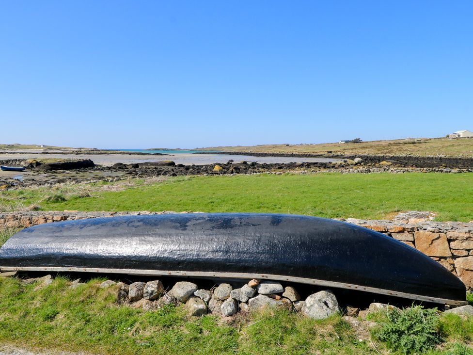 A boat on grass near water at Claddagh Tuss Holiday Cottage in Clifton