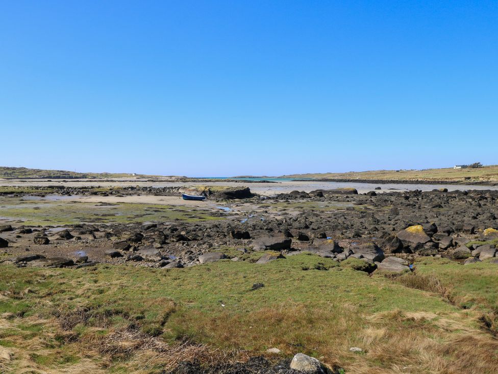 A coastal area with rocks and a boat at Claddagh Tuss Holiday Cottage in Clifton