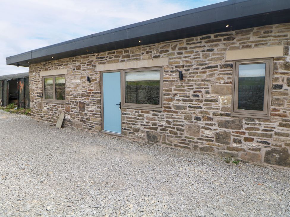An exterior view of a stone building with a blue door at The Stables in Stockport