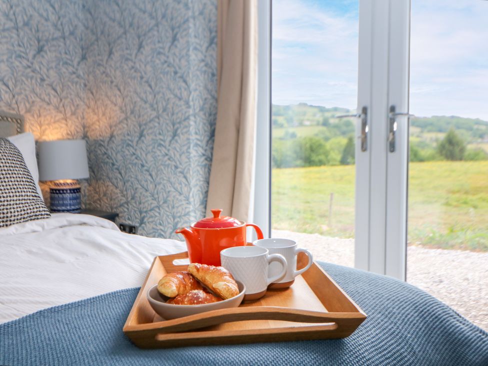 A bedroom with a tray of tea and pastries on a bed at The Stables in Stockport