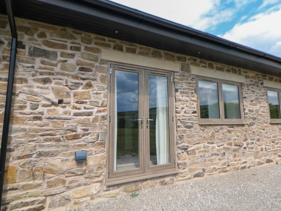 Exterior view of a stone wall with double doors and windows at The Stables in Stockport