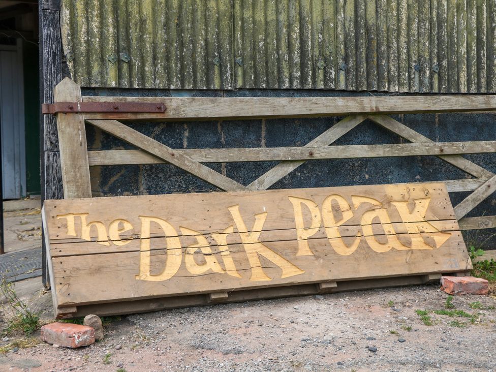 A wooden sign for The Dark Peak by a gate