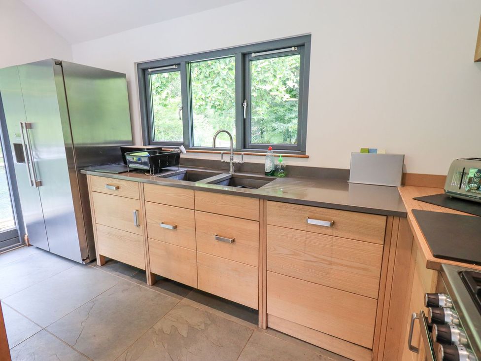 A kitchen with cabinets, sink, and fridge at Bracken Ground in Coniston