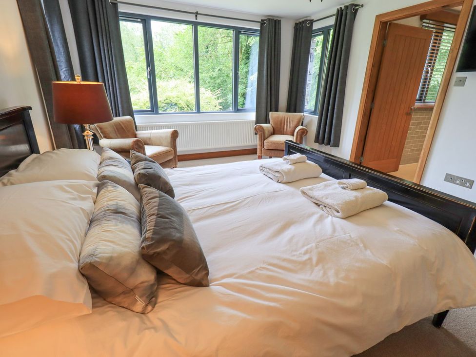 A bedroom with a bed and armchairs at Bracken Ground in Coniston