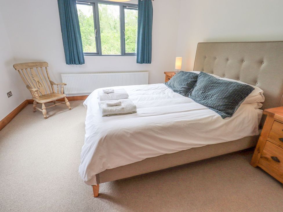 A bedroom with a bed, bedside table, and rocking chair at Bracken Ground in Coniston