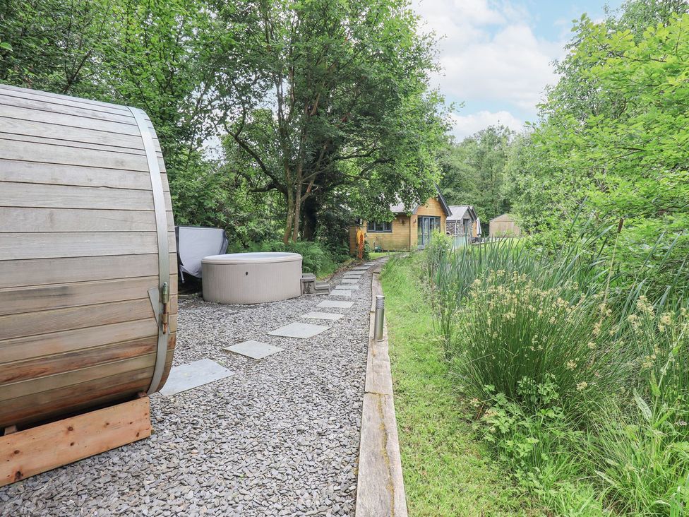 An outdoor area with a hot tub and a barrel sauna at Bracken Ground in Coniston