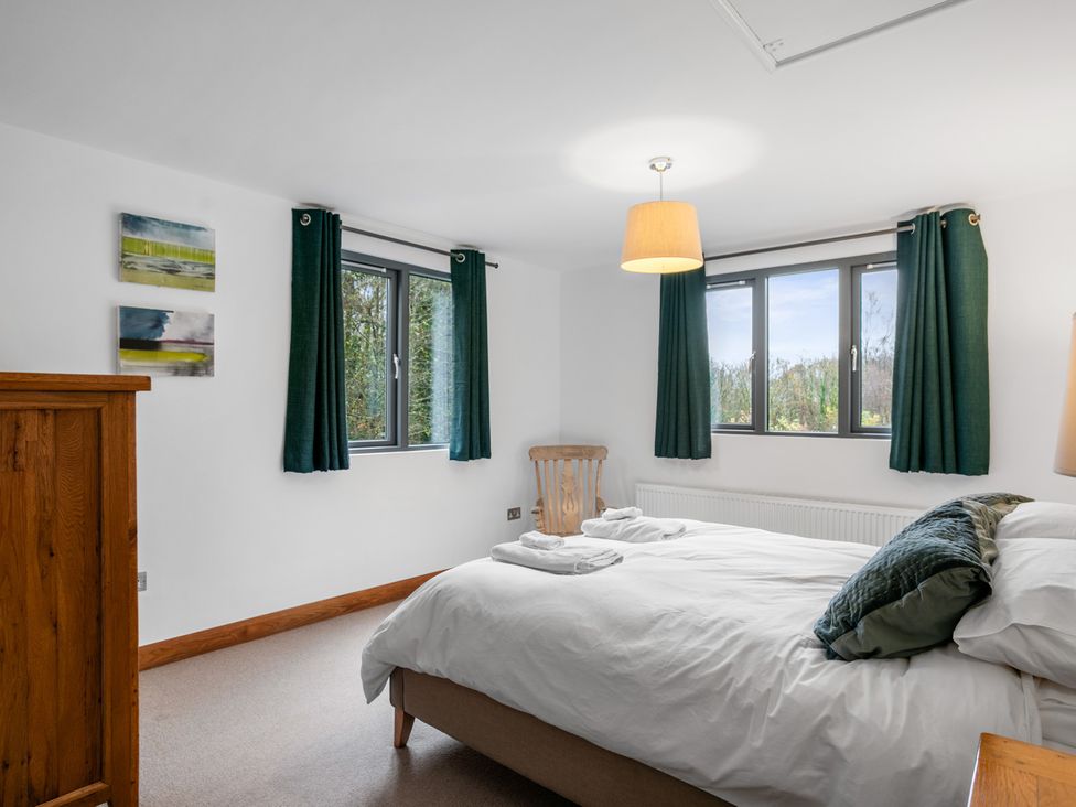 A bedroom with a bed and windows at Bracken Ground in Coniston