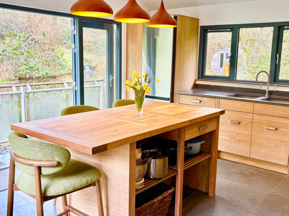 A kitchen with a wooden island and bar stools at Bracken Ground in Coniston