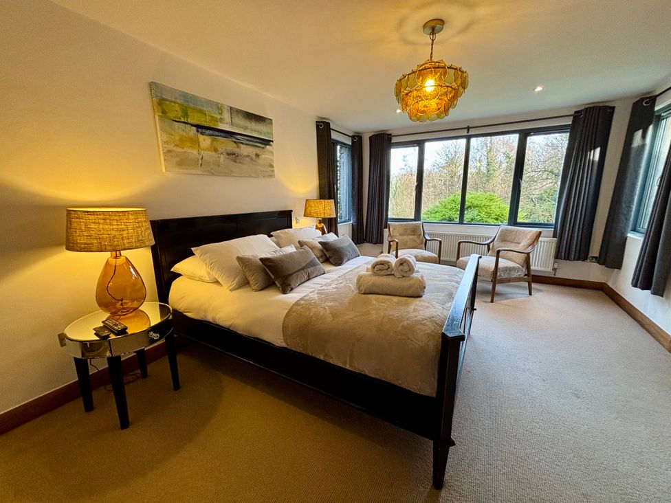 A bedroom with a bed and large windows at Bracken Ground in Coniston