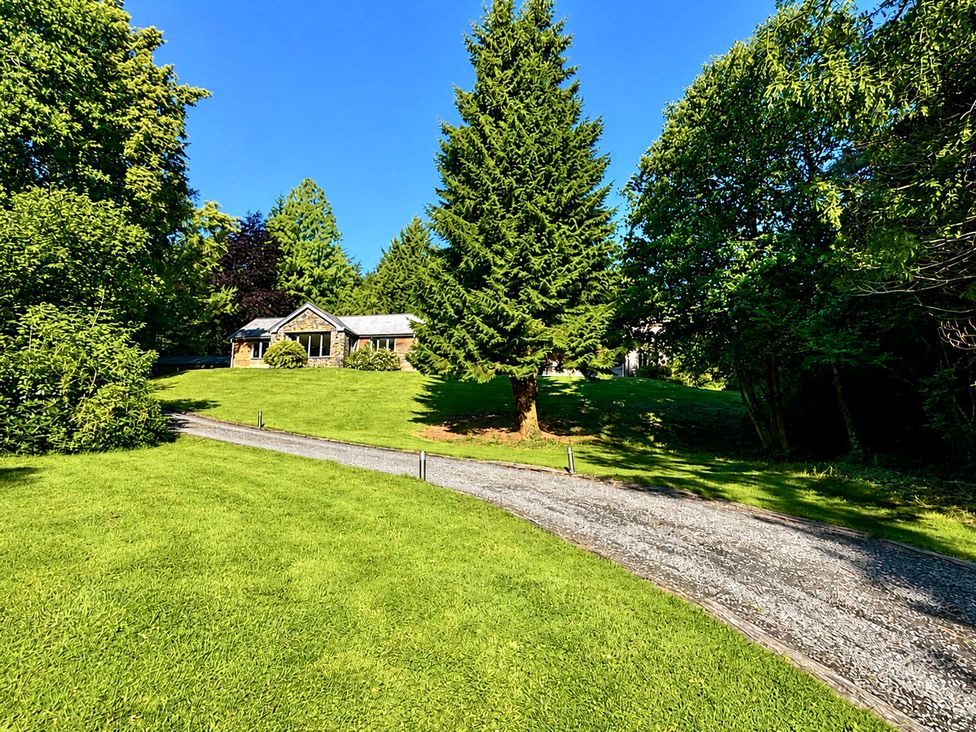 A house with surrounding trees and a gravel driveway at Bracken Ground in Coniston