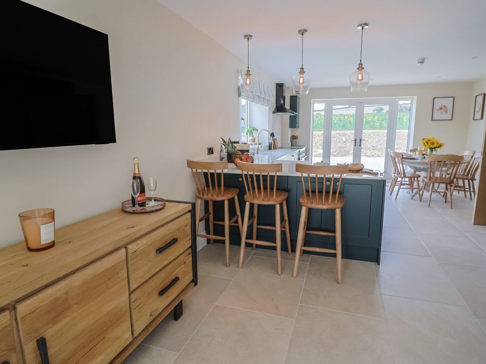 A kitchen with bar stools and a dining table at Foxes Den in Pendomer near Yeovil, Somerset