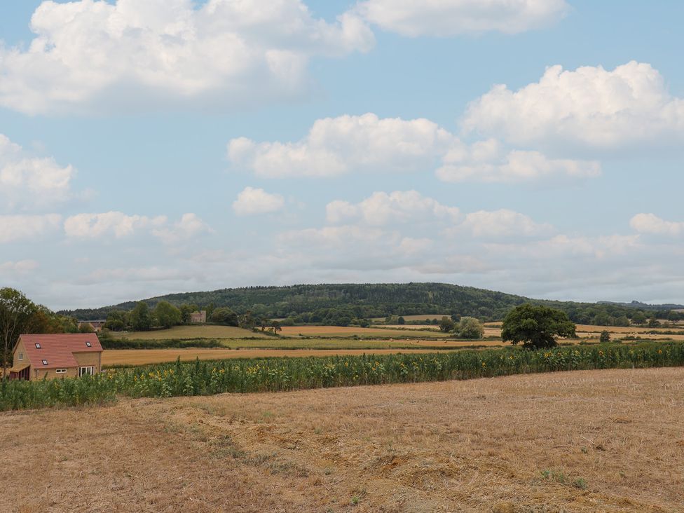 A landscape view with a house, fields, and hills at Foxes Den, Pendomer near Yeovil, Somerset