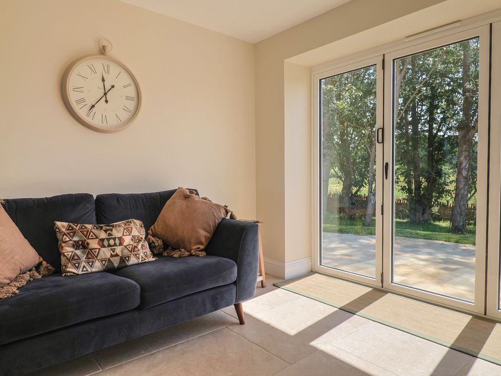 A snug with a sofa and clock at The Fox Den in East Coker
