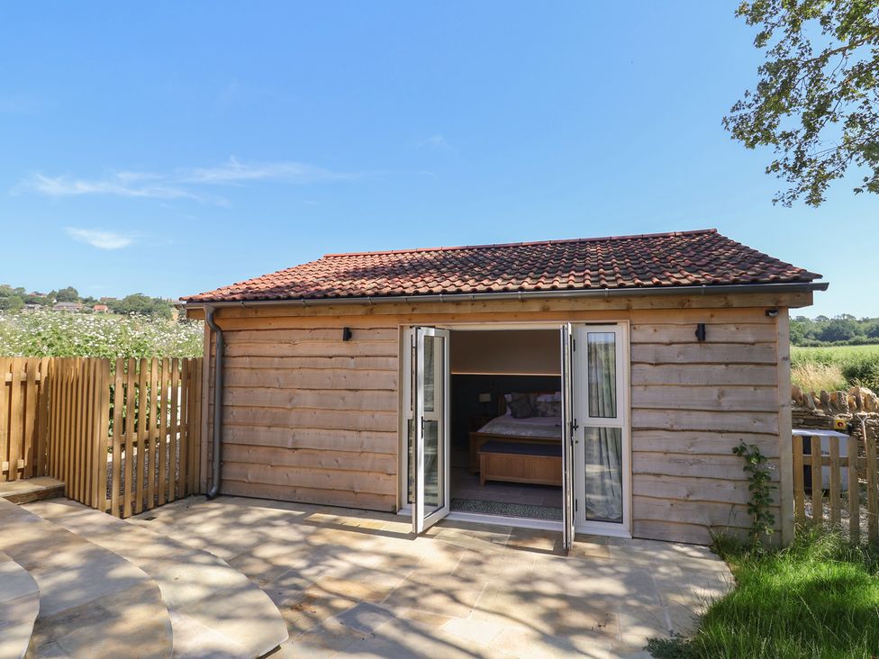 A wooden cabin with sliding doors and an outdoor patio at The Fox Den in East Coker