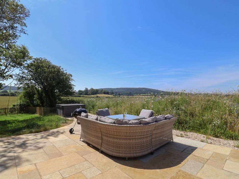An outdoor seating area with a table and view of fields at The Fox Den in East Coker