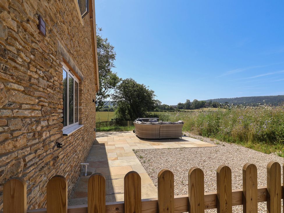 An outdoor area with a stone wall and seating at The Fox Den in East Coker