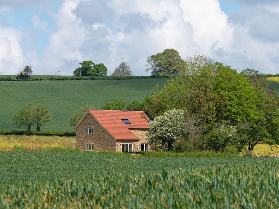 A house surrounded by fields and trees at The Fox Den in East Coker