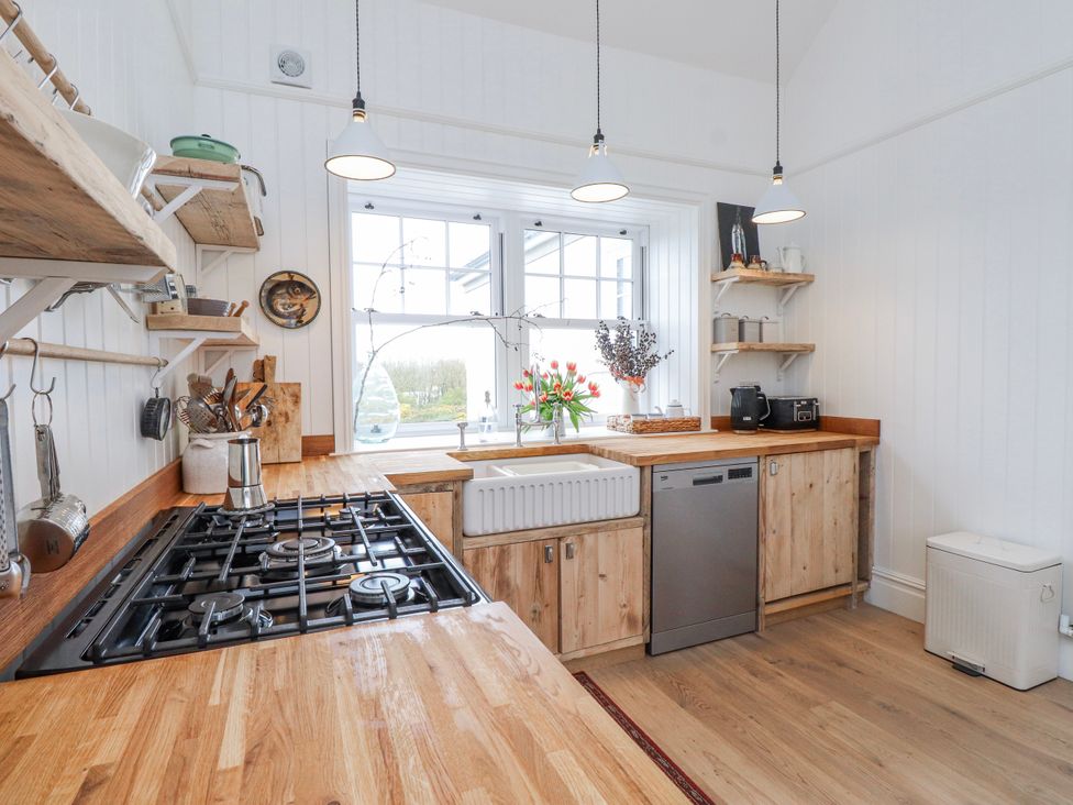 A kitchen with a gas stove, sink, and shelves at 4 bed in Anglesey
